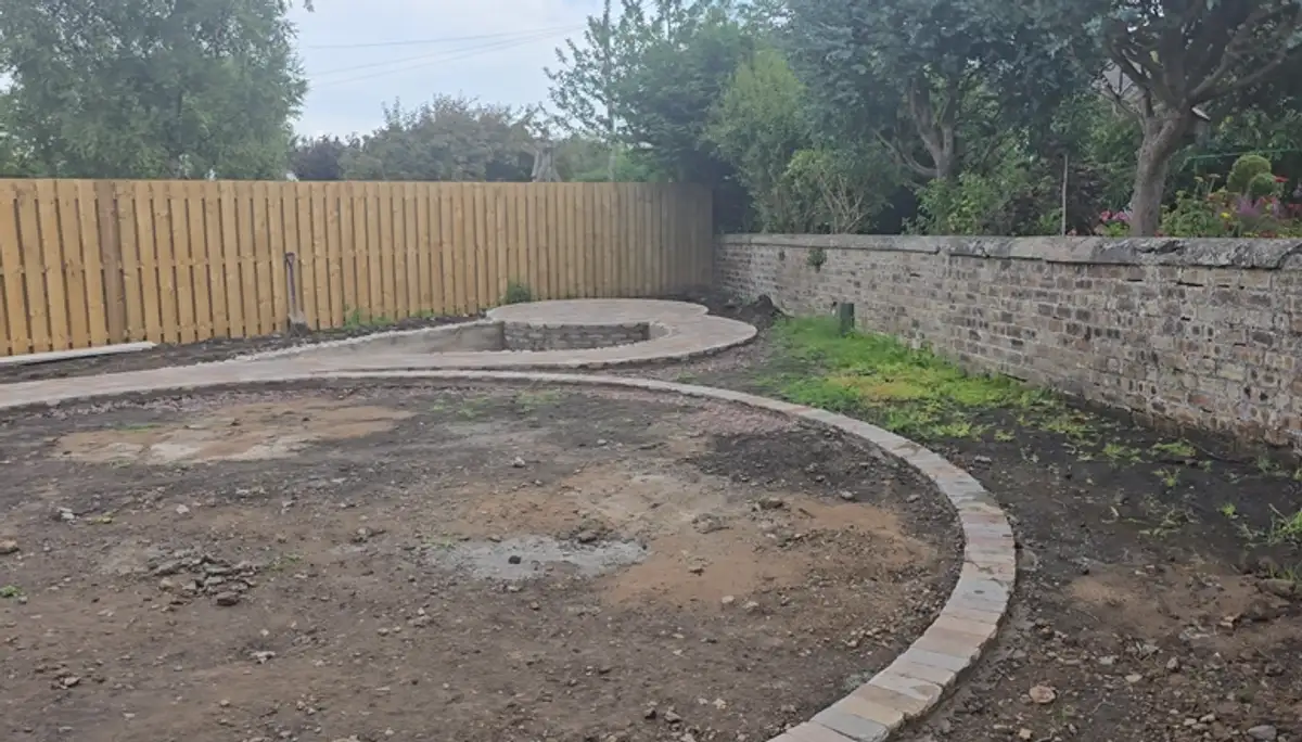 Curved brick edging and the circular concrete pond surround taking shape on the prepared ground