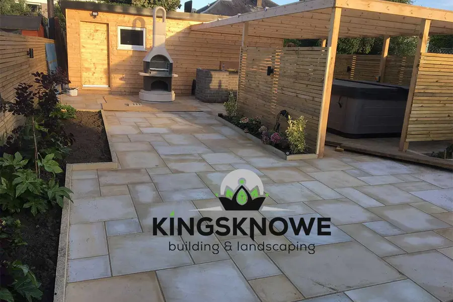 A hot tub on a sandstone patio under a timber pergola in a landscaped Edinburgh garden